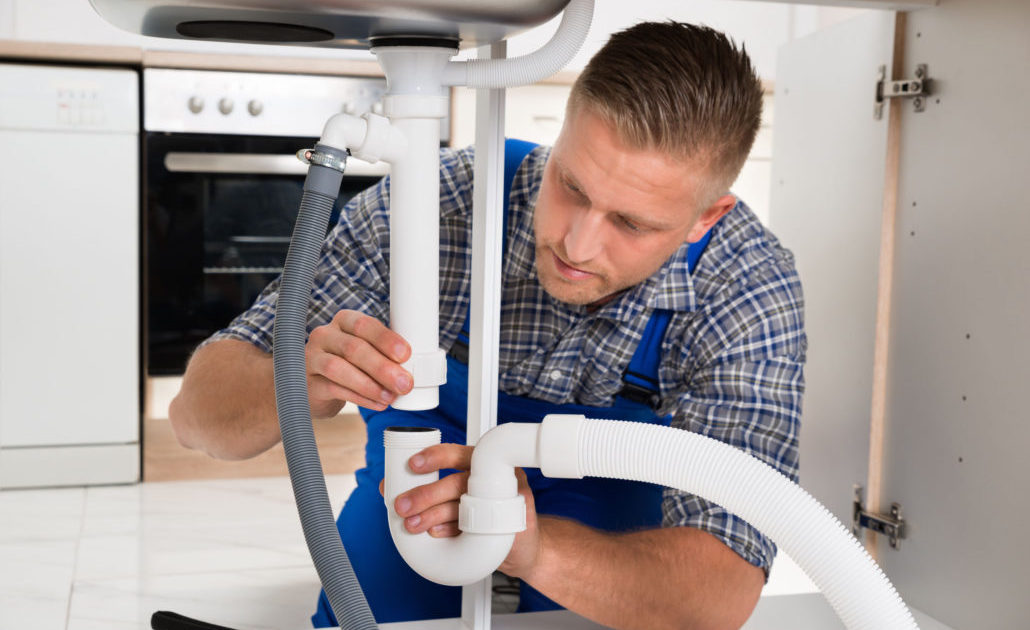 43693569 - young plumber repairing pipe of sink in kitchen